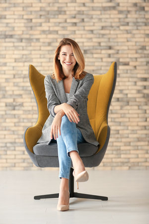 Young woman sitting in armchair indoorsの写真素材