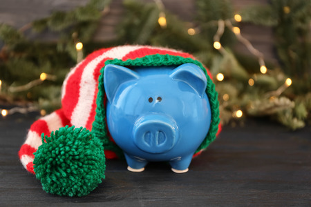 Piggy bank with striped hat and blurred Christmas lights on backgroundの写真素材