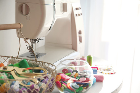 Modern sewing machine with threads on tableの写真素材