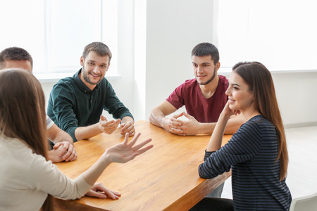 Group of young people sitting at table together, indoors. Unity concept