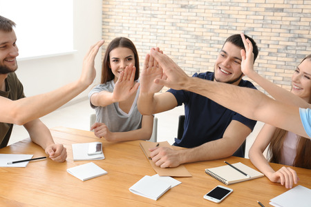 People giving high five at table. Unity concept