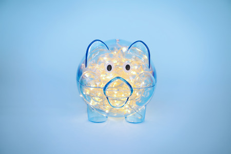 Piggy bank with Christmas garland on color backgroundの写真素材