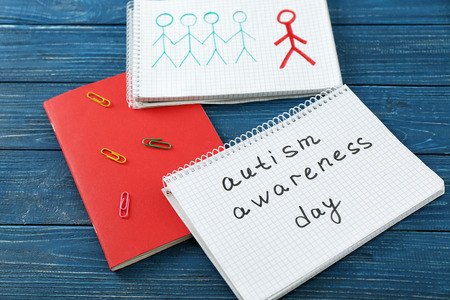 Notepad with text AUTISM AWARENESS DAY on wooden backgroundの写真素材