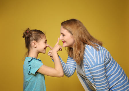 Happy mother and daughter having fun on color backgroundの写真素材