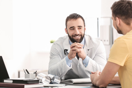 Doctor consulting male patient in clinicの写真素材