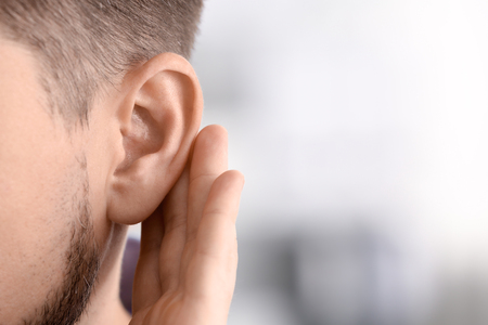 Mature man with hearing problem on blurred  background, closeup