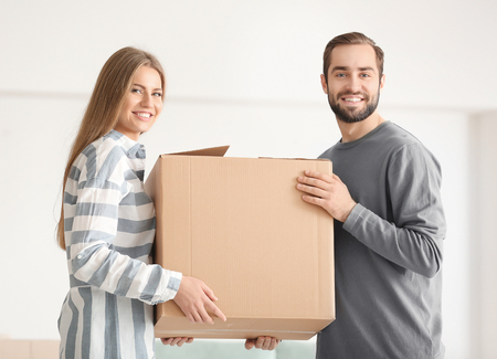 Young couple with moving box in room at new homeの写真素材