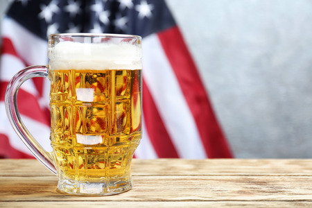 Glass of beer on table against American flag backgroundの写真素材