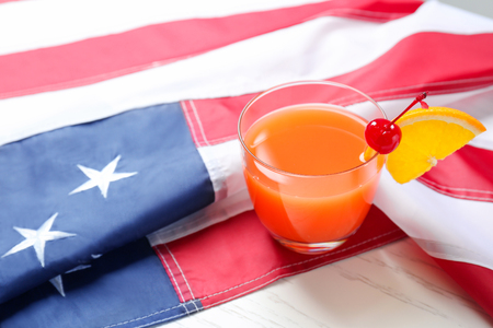 Glass with alcoholic cocktail and American flag on tableの写真素材