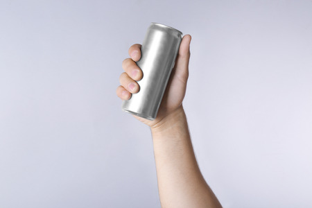 Male hand with aluminum can on light backgroundの写真素材