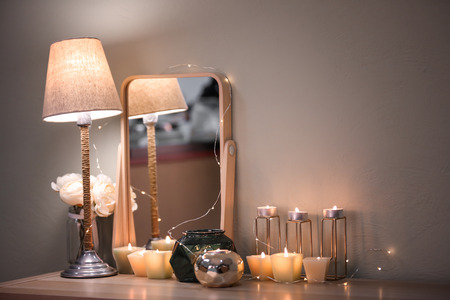 Burning candles and modern mirror on tableの写真素材