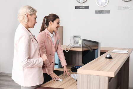 Female receptionist teaching trainee in hotelの写真素材