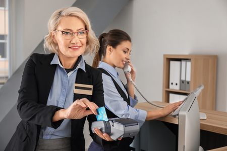 Female receptionist receiving payment for hotel room from client in hotelの写真素材