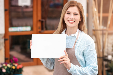 Business owner holding blank paper near her store, outdoorsの写真素材