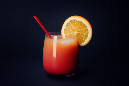 Glass of Sex on the Beach cocktail against dark background