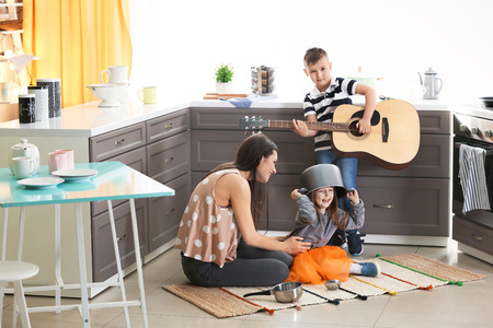 Family with kitchenware and guitar playing at homeの写真素材