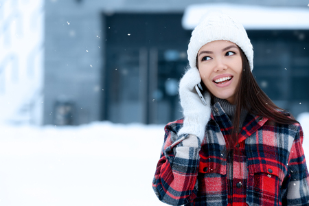 Beautiful young woman talking on mobile phone outdoors on winter dayの写真素材