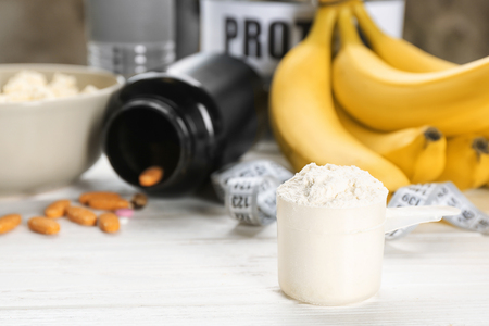 Scoop with protein powder and products on tableの写真素材