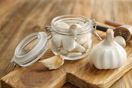Jar with garlic cloves and head on boardの写真素材