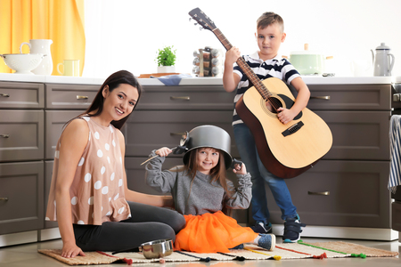 Family with kitchenware and guitar playing at homeの写真素材