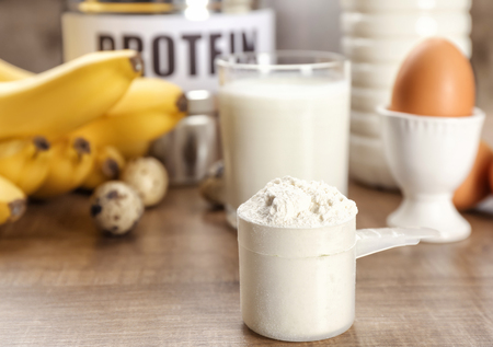 Scoop with protein powder and products on tableの写真素材