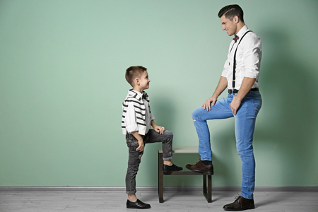 Stylish father and son against color wallの写真素材