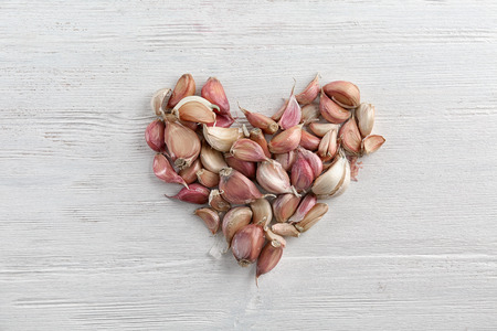 Heart shape of fresh garlic on white wooden backgroundの写真素材