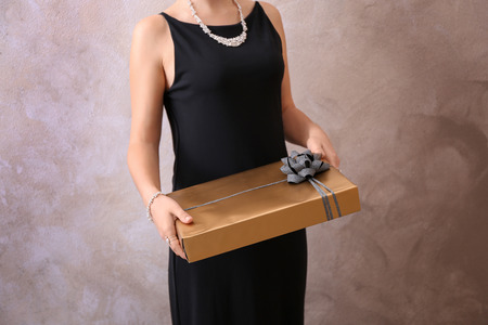 Young woman holding gift box on light backgroundの写真素材