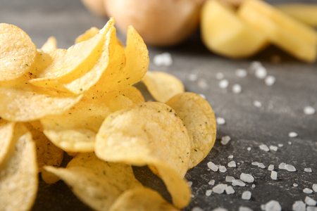 Yummy crispy potato chips with salt on grey tableの写真素材