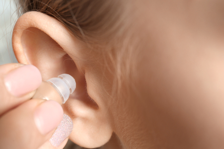 Young woman putting hearing aid in ear, closeupの写真素材