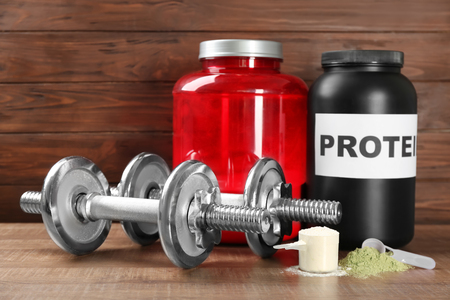 Composition with protein powder and dumbbells on wooden backgroundの写真素材