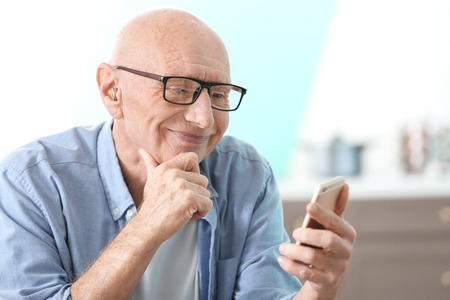 Hearing impaired man with phone at homeの写真素材