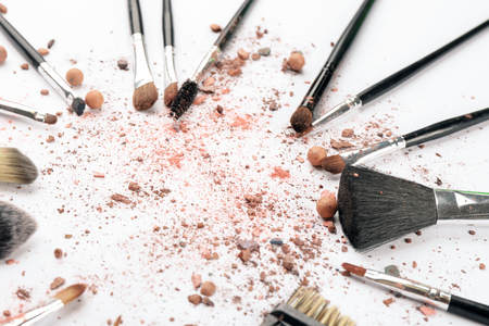 Makeup brushes with crushed cosmetic of professional artist on white backgroundの写真素材