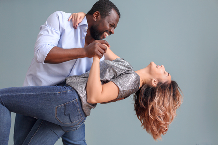 Cute interracial couple dancing against color backgroundの写真素材