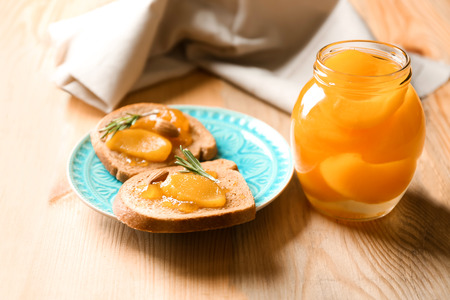 Jar and slices of bread with pickled apricots on tableの写真素材