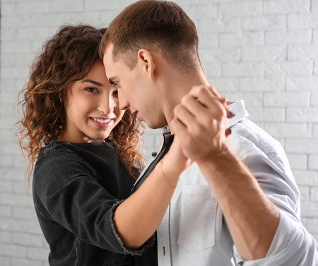 Young loving couple dancing in light room