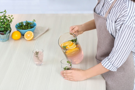 Young woman with tasty lemonade in kitchenの写真素材