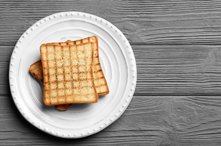 Plate with tasty toasted bread on wooden tableの写真素材