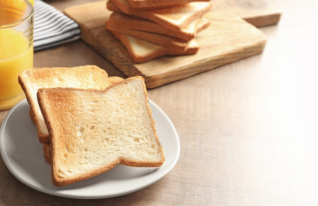Plate with tasty toasted bread on wooden table