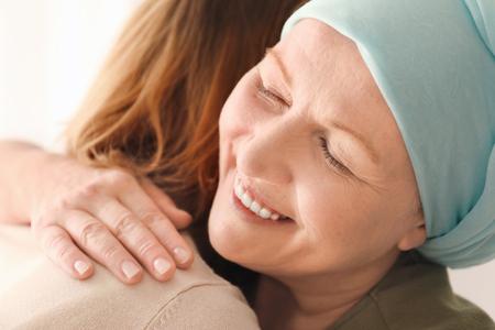 Woman hugging her mother with cancer indoorsの写真素材