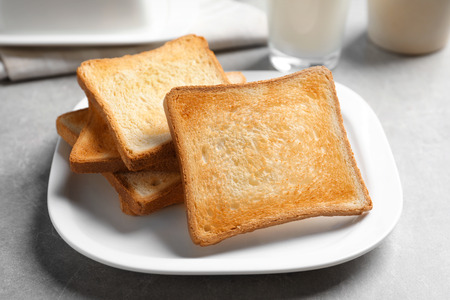 Plate with tasty toasted bread on table