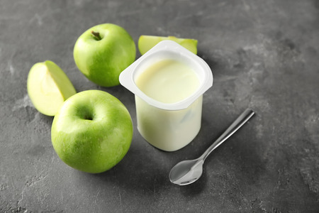 Plastic cup with yummy apple yogurt on tableの写真素材