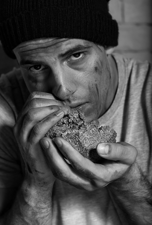 Hungry poor man eating piece of breadの写真素材