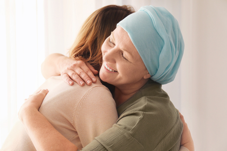 Woman hugging her mother with cancer indoorsの写真素材