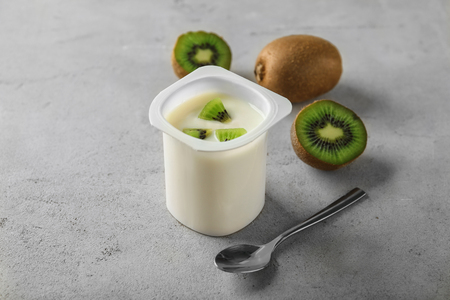 Plastic cup with yummy kiwi yogurt on tableの写真素材