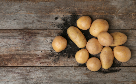 Fresh raw potatoes on wooden table, top viewの写真素材