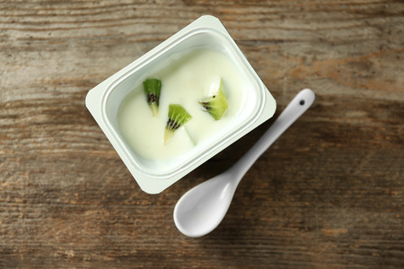 Plastic cup with yummy kiwi yogurt on wooden tableの写真素材