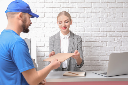 Female receptionist receiving parcel at workplaceの写真素材