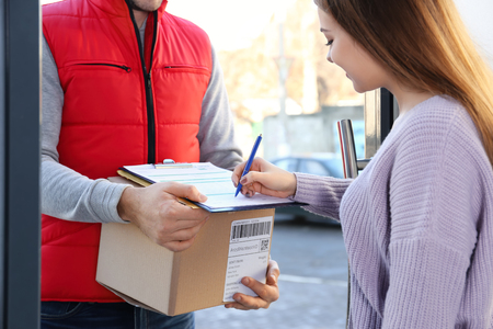 Woman signing for parcel delivery at doorwayの写真素材