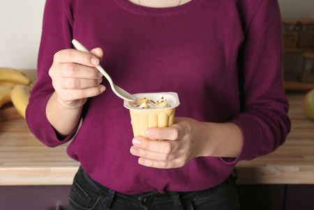 Woman eating yogurt with pieces of banana indoors, closeupの写真素材